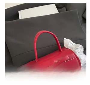 Detail of red leather mini bag with decorative bow and white embroidered lace trim