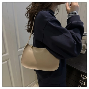 Close-up of minimalist beige hobo shoulder bag with zipper and fine stitching details