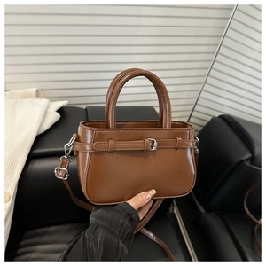 Détail du sac bandoulière en similicuir marron avec sangle décorative et boucle métal