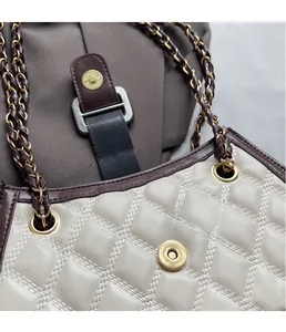 Dettaglio borsa trapuntata beige con chiusura dorata e tracolla in catena di pelle