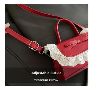 Detail of red lace handbag showing adjustable silver buckle and heart trim