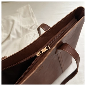 Gros plan sur la fermeture éclair dorée et le cuir marron lisse d'un sac cabas