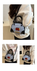 Detail showing red apple print on blue gingham crossbody bag with leather trim and strap
