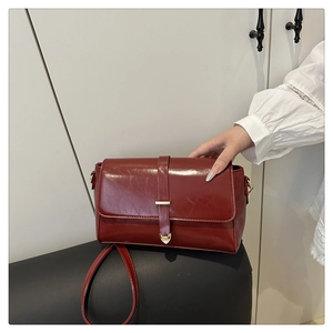 Détail du cuir ciré rouge foncé avec boucle dorée en forme de cœur sur le sac à main