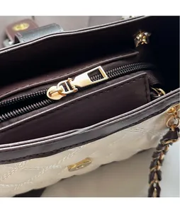 Dettaglio dell'esterno trapuntato beige con fodera marrone e cerniera in metallo dorato