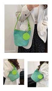 Détail du sac seau vert menthe avec bandoulière à nœuds vert vif et pendentif rond