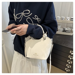 Détail du sac seau blanc à texture plissée avec poignée cordelette et logo chic