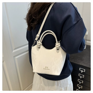 Vue arrière d'un mannequin portant un sac seau blanc minimaliste avec poignée nouée