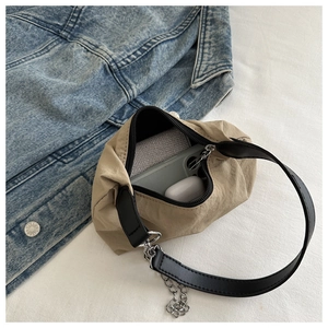Minimalist beige canvas crossbody bag with black leather handle and metal chain detail
