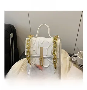 Detail shot of white leather bag with branch leaf embossment and gold chain accents