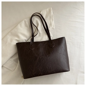 Détail du grand sac cabas vintage marron foncé posé sur une veste en velours blanc