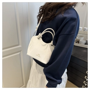 Détail d'un sac seau blanc avec texture marbrée et anses nouées rondes pour femmes