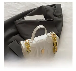 Detail shot of white embossed leaf pattern and golden chain handle on the bag