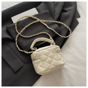 Top view of beige quilted mini box bag with chain strap on a black blazer background