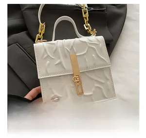 Detail of white embossed underarm bag featuring 3D branch texture and gold chain strap