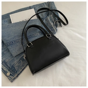 Detailed view of black semi-circular handbag with silver hardware and thin shoulder strap
