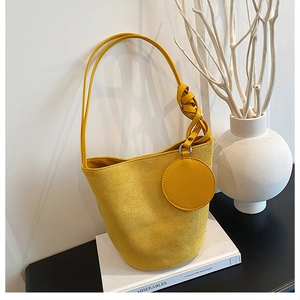 Gros plan du sac seau en velours jaune avec bandoulière nouée et porte-monnaie rond
