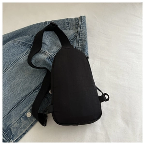 Flat lay of a waterproof black nylon sling bag on a casual denim jacket background