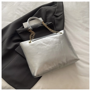 Detail of silver tote bag showing crinkle faux leather texture and golden chain straps
