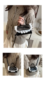 Detail of black mini crossbody bag featuring white lace trim and black bow decoration