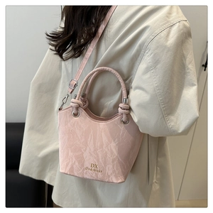 Gros plan sur un sac seau rose plissé avec poignées nouées et crochets argentés