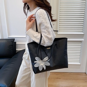 Retro black oversized tote bag with floral charm shown on shoulder for daily commute