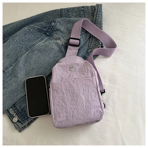 Close-up of lavender waterproof nylon chest bag with metallic M logo and adjustable strap