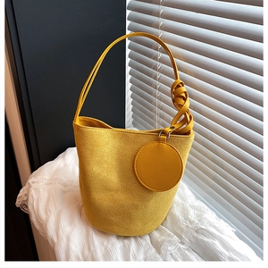 Détail de sac seau en daim jaune avec petite pochette ronde et bandoulière tressée chic