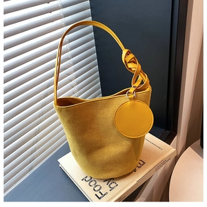 Détail du sac seau jaune en simili daim avec poignée nouée et pochette ronde assortie