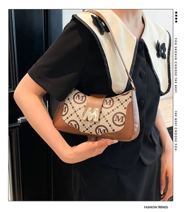 Detail of vintage underarm bag featuring jacquard M-pattern and gold metal M-clasp buckle
