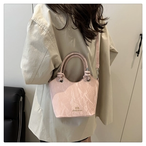 Détail du sac seau rose clair avec texture froissée et poignée métallique chic