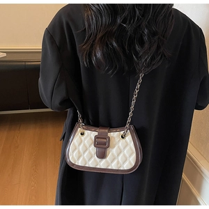 Close-up of quilted cream leather bag with contrast brown trim and gold chain strap