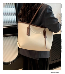Detail of a large cream and brown tote bag shown on a model for a stylish commute look