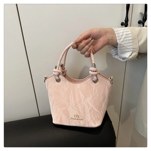 Détail du sac à main rose clair montrant la texture marbrée et le logo DX doré