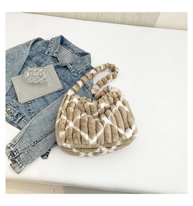Detail view of plush striped tote bag featuring geometric patterns and fluffy bead handle