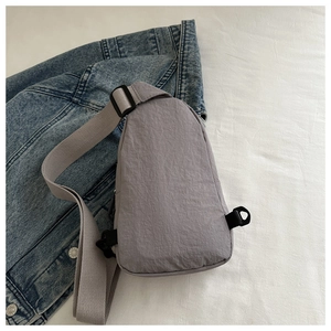 Detailed close-up of grey waterproof nylon chest bag on denim jacket backdrop