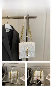 Detail of white square bag with coral textured embossing and gold chain strap