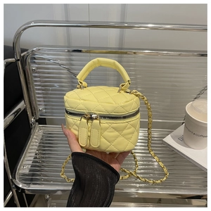 Detail of yellow quilted mini box bag with chain strap and elegant top handle