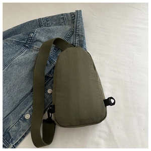 Olive green waterproof nylon chest bag with adjustable strap on denim background