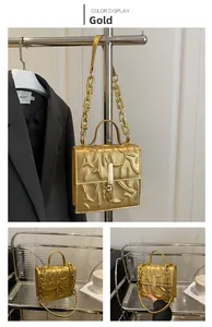 Detail of gold textured crossbody bag with metal handle and chunky chain strap