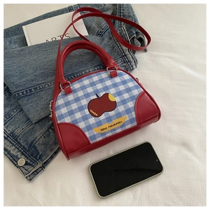 Detail of blue plaid canvas tote with red leather trim and cartoon apple print