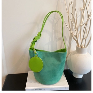 Détail du sac seau en daim vert menthe avec anse tressée et mini pochette