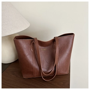 Gros plan d'un sac cabas en cuir marron avec lettrage doré élégant sur un bureau en bois