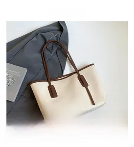 Detail view of large cream tote bag with brown straps and sleek side loop accents