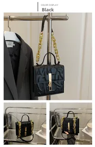 Detail of black structured handbag featuring branch-like embossed texture and gold chain