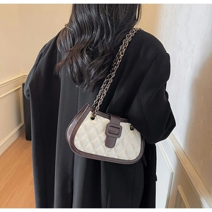 Dettaglio della borsa trapuntata bianca con bordi in pelle marrone scuro e tracolla a catena