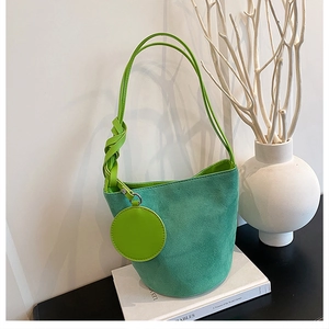 Détail du sac seau vert foncé mat avec bandoulière nouée et petit porte-monnaie
