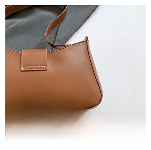 Detailed close-up of brown faux leather shoulder bag with fine stitching and smooth texture