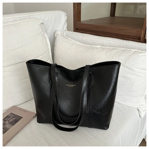 Détail du logo doré sur le sac fourre-tout minimaliste en cuir noir de haute qualité
