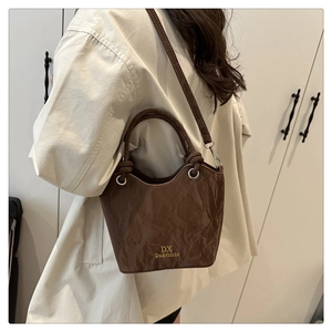 Vue détaillée du sac seau marron plissé avec logo doré et anneaux métalliques ronds